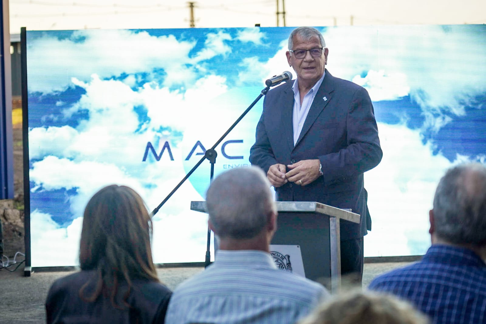 A speaker presenting environmental technology in front of a MACOMA backdrop